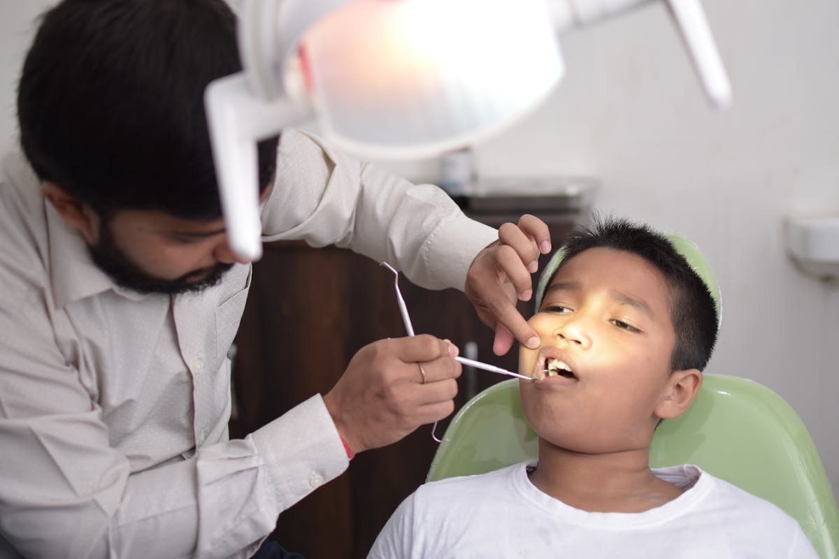 Dentist examining a young boy's teeth in the dental chair