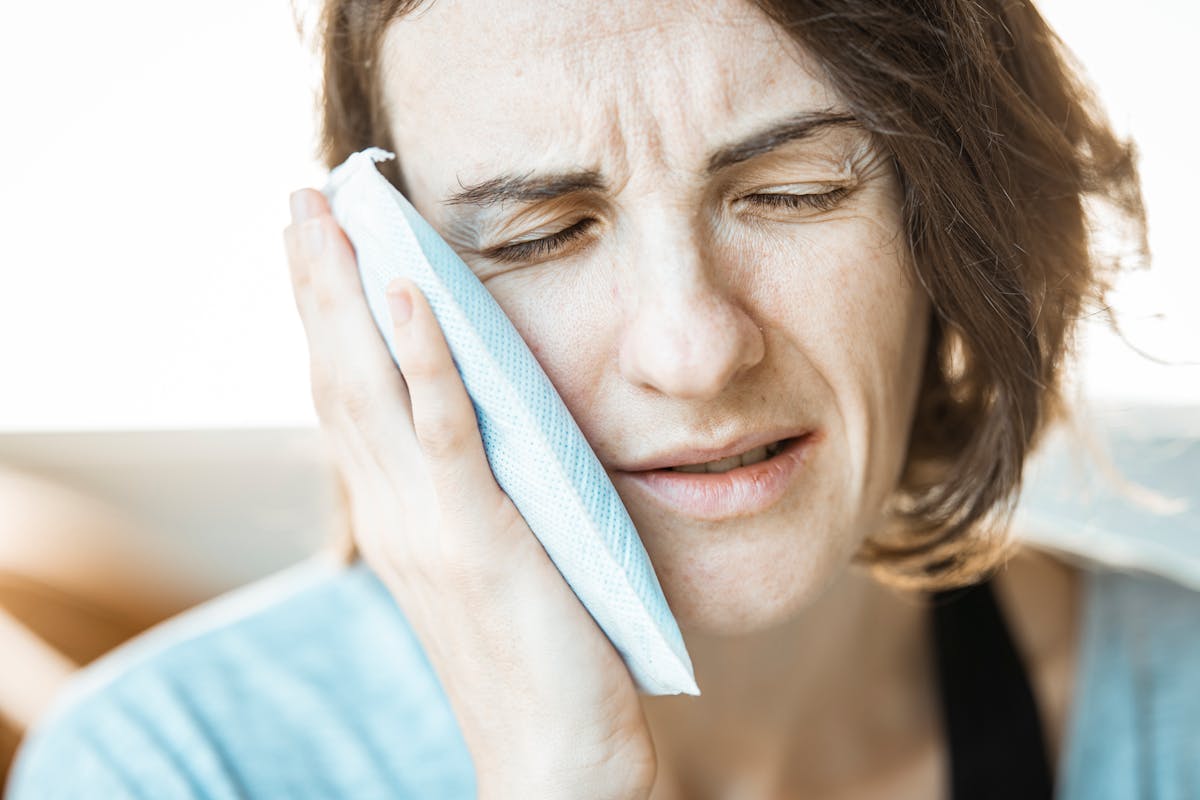Woman holding a cold compress against her cheek because of tooth pain