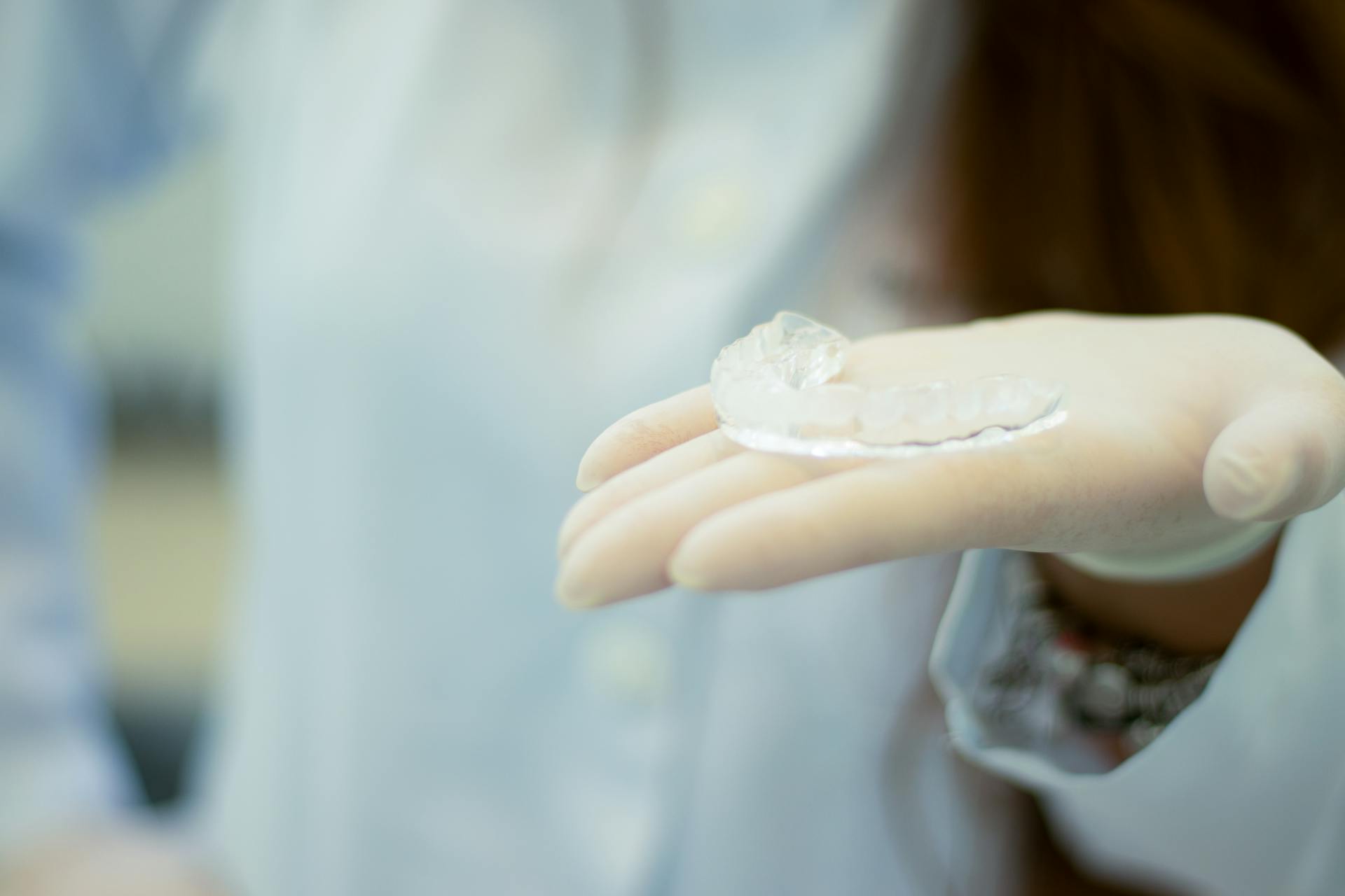 Gloved hand holding a clear custom dental appliance