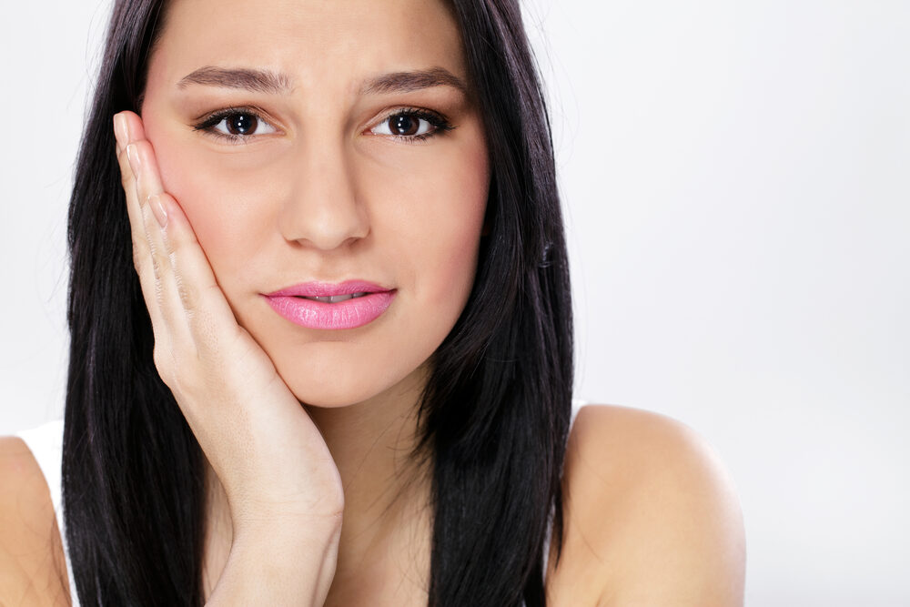 Woman holding the side of her jaw in discomfort