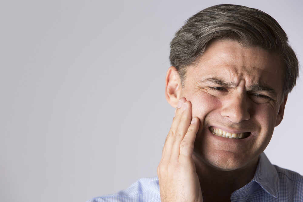 Man holding his jaw in discomfort